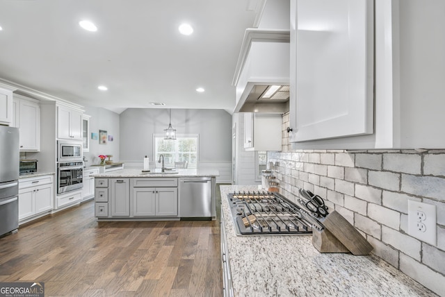 kitchen with white cabinets, light stone countertops, appliances with stainless steel finishes, and dark hardwood / wood-style flooring