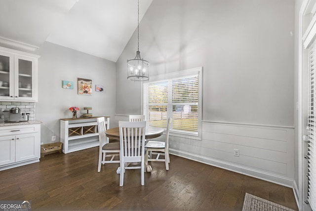 dining area featuring dark hardwood / wood-style flooring, high vaulted ceiling, and a chandelier