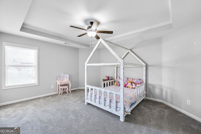 carpeted bedroom with ornamental molding, ceiling fan, and a tray ceiling