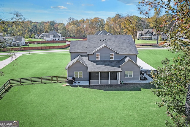 rear view of house featuring a lawn and a sunroom