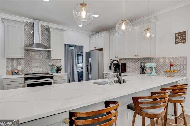 kitchen with a kitchen bar, appliances with stainless steel finishes, tasteful backsplash, and wall chimney range hood