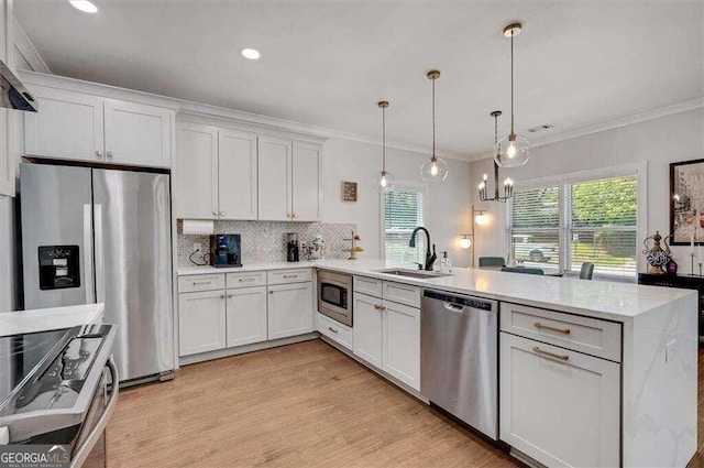 kitchen featuring hanging light fixtures, sink, white cabinetry, light wood-type flooring, and appliances with stainless steel finishes