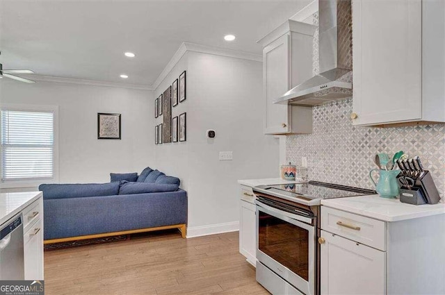 kitchen with stainless steel appliances, wall chimney exhaust hood, white cabinets, and light hardwood / wood-style flooring