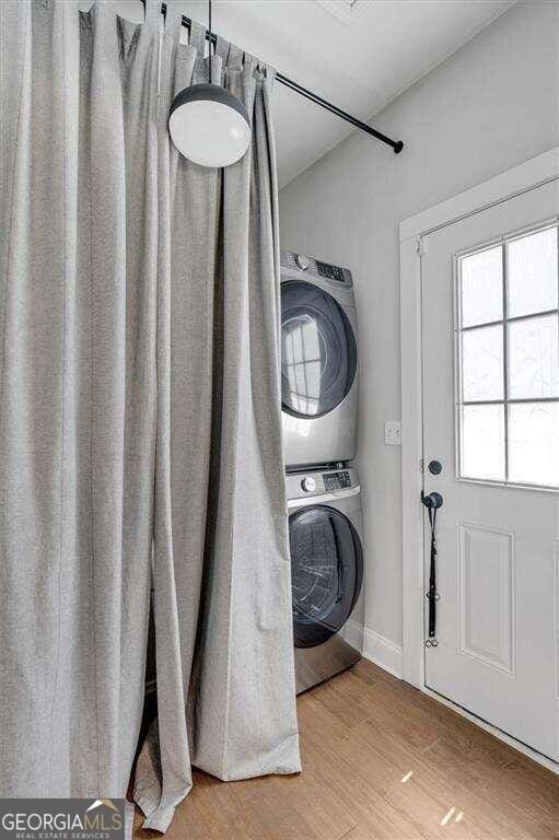 laundry area with light wood-type flooring and stacked washer and clothes dryer