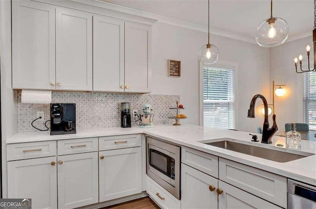 kitchen featuring ornamental molding, appliances with stainless steel finishes, decorative light fixtures, sink, and white cabinets