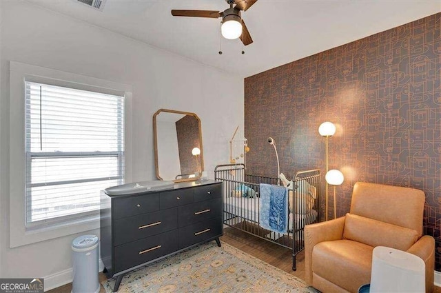 bedroom featuring a crib, light hardwood / wood-style flooring, and ceiling fan