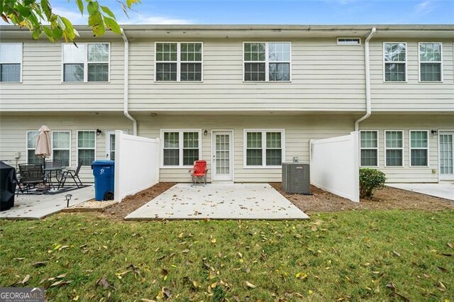 back of house featuring central air condition unit, a patio area, and a lawn