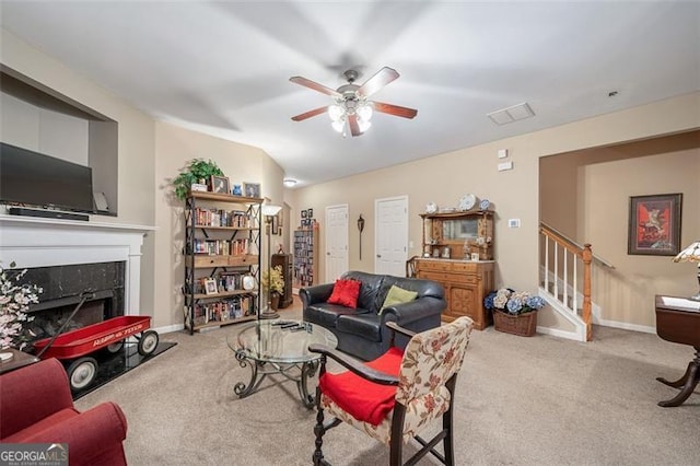 living room featuring a fireplace, light carpet, and ceiling fan