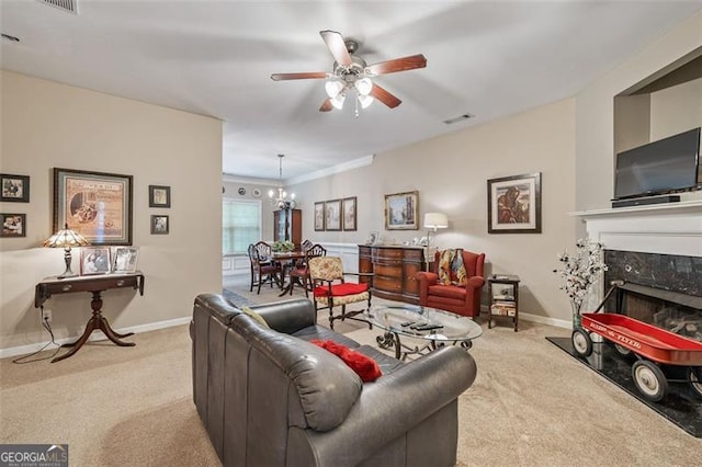 living room featuring a fireplace, ceiling fan with notable chandelier, light carpet, and crown molding