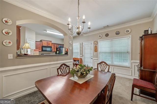 carpeted dining area featuring a notable chandelier and ornamental molding