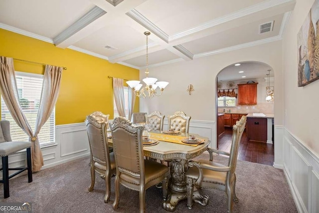 dining space featuring dark wood-type flooring, beamed ceiling, crown molding, and a notable chandelier