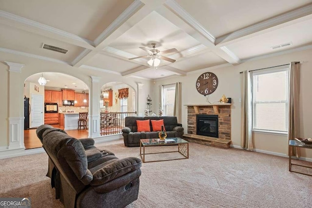 living area featuring arched walkways, coffered ceiling, visible vents, and ornate columns