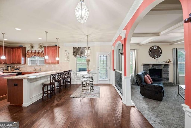 kitchen featuring light stone counters, a kitchen breakfast bar, open floor plan, a fireplace, and pendant lighting