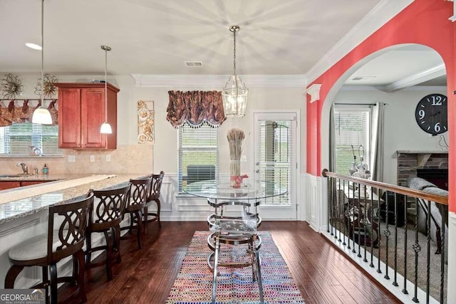 dining room featuring crown molding, arched walkways, dark wood finished floors, and a healthy amount of sunlight