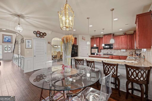 dining space with dark wood-type flooring, sink, a notable chandelier, and ornamental molding