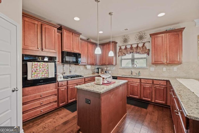 kitchen with black appliances, light stone countertops, dark hardwood / wood-style floors, decorative light fixtures, and a kitchen island