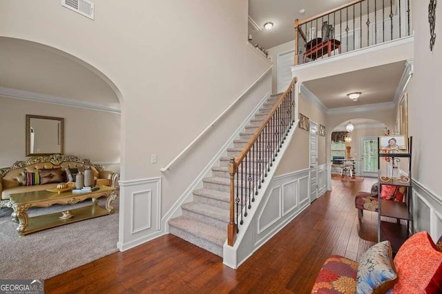 staircase with hardwood / wood-style floors and crown molding