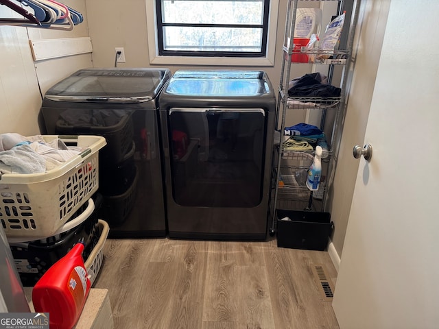 clothes washing area featuring light hardwood / wood-style floors and separate washer and dryer