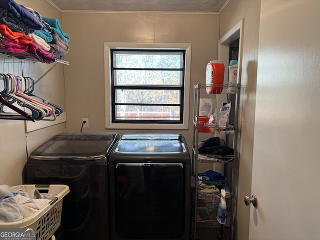 laundry area featuring wooden walls, a textured ceiling, and separate washer and dryer