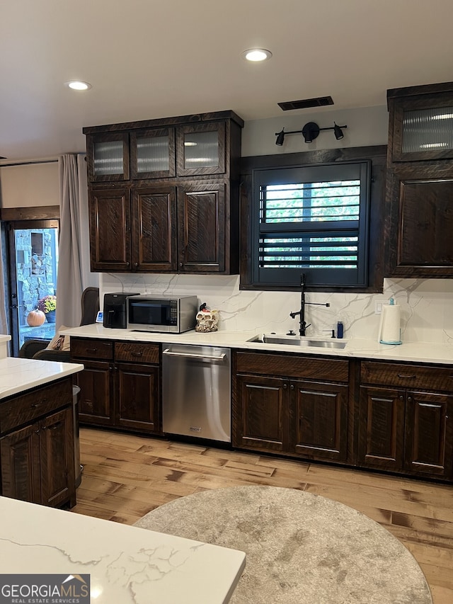 kitchen with dark brown cabinetry, light hardwood / wood-style floors, appliances with stainless steel finishes, and sink