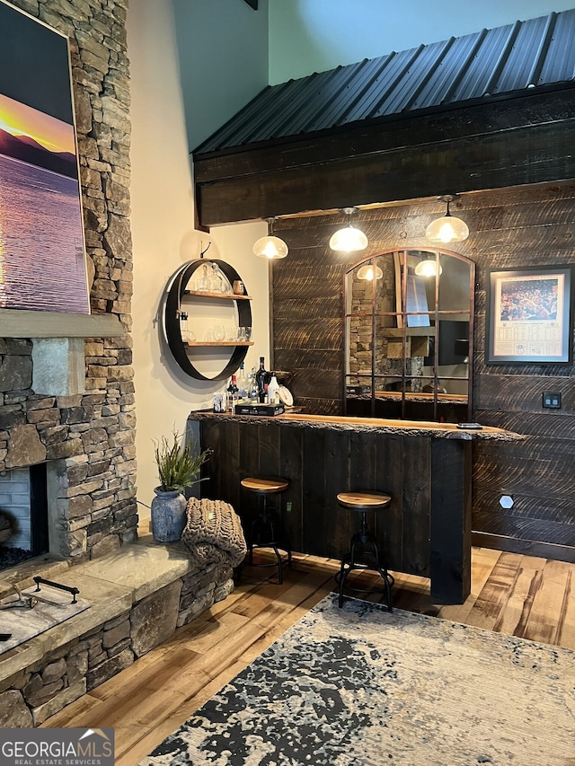 bar with a high ceiling, a fireplace, and light hardwood / wood-style flooring