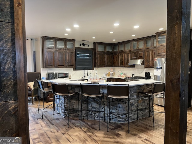 330 E Second St, Blue Ridge, GA 30513 - kitchen featuring stainless steel refrigerator with ice dispenser, under cabinet range hood, light wood finished floors, decorative backsplash, and dark brown cabinetry