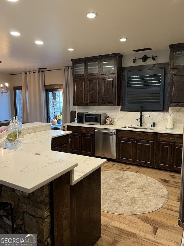 kitchen with sink, a breakfast bar, appliances with stainless steel finishes, dark brown cabinets, and light hardwood / wood-style flooring