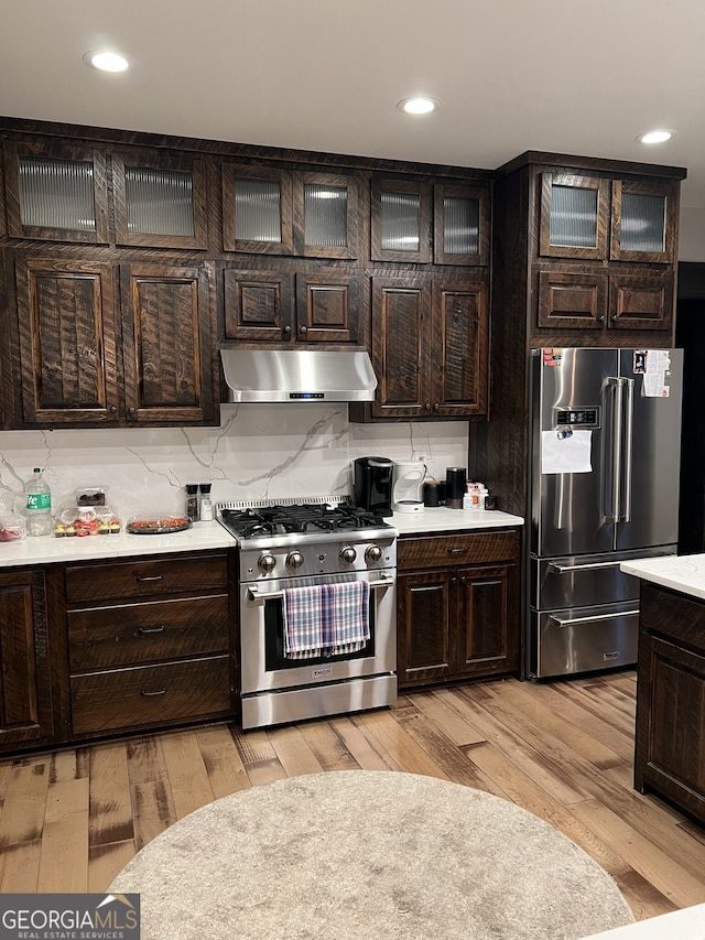 kitchen featuring dark brown cabinetry, high quality appliances, and light hardwood / wood-style flooring