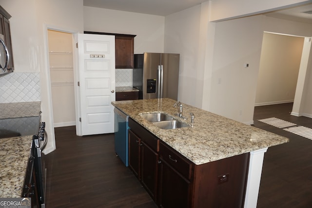 kitchen with a kitchen island with sink, stainless steel appliances, sink, and tasteful backsplash