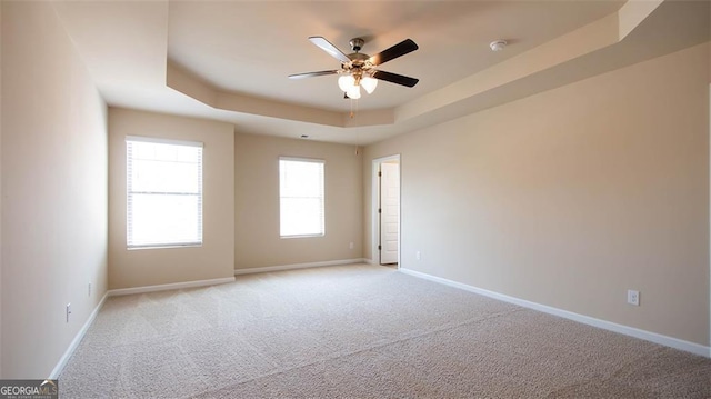 unfurnished room featuring light colored carpet, ceiling fan, and a tray ceiling