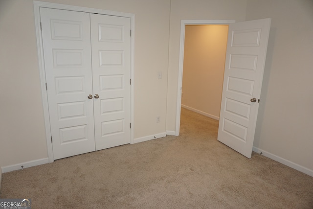 unfurnished bedroom with light colored carpet and a closet