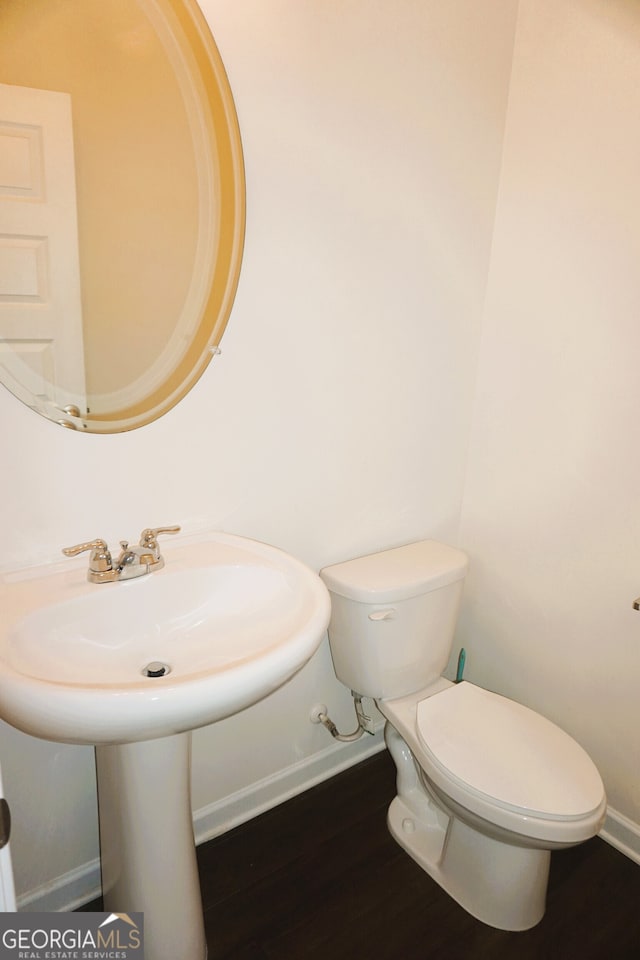 bathroom with wood-type flooring, toilet, and sink