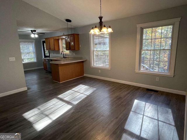 kitchen with ceiling fan with notable chandelier, dark wood-type flooring, kitchen peninsula, hanging light fixtures, and sink