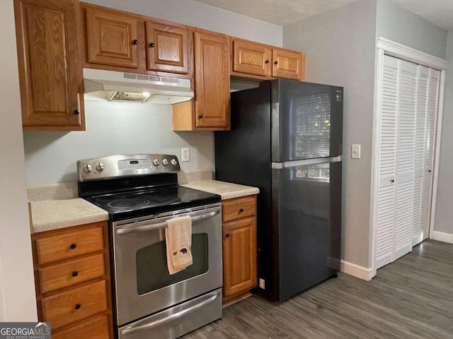 kitchen with black fridge, dark wood-type flooring, and stainless steel range with electric cooktop