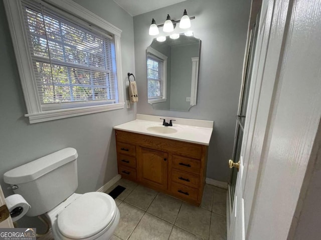 bathroom with toilet, vanity, tile patterned floors, and a healthy amount of sunlight