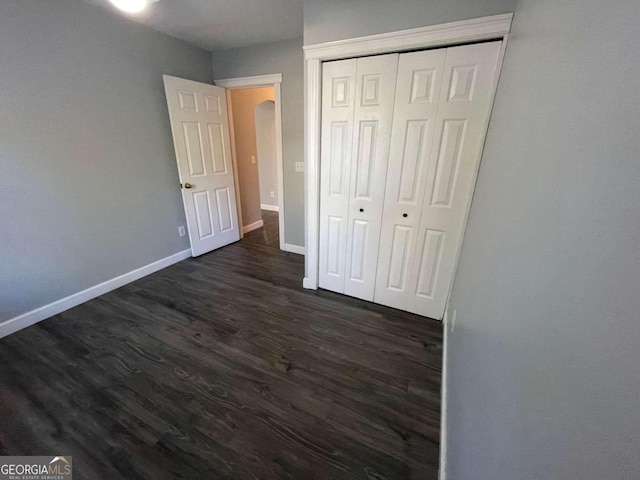 unfurnished bedroom with dark hardwood / wood-style floors and a closet