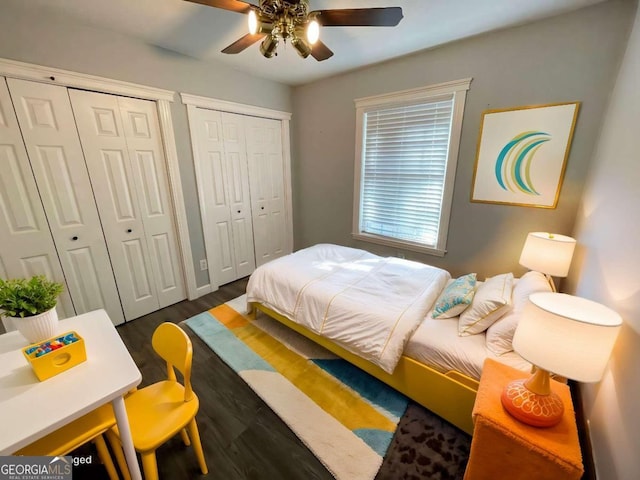 bedroom with multiple closets, dark hardwood / wood-style flooring, and ceiling fan