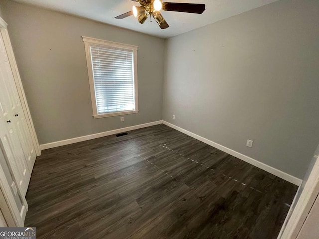 empty room with dark wood-type flooring and ceiling fan