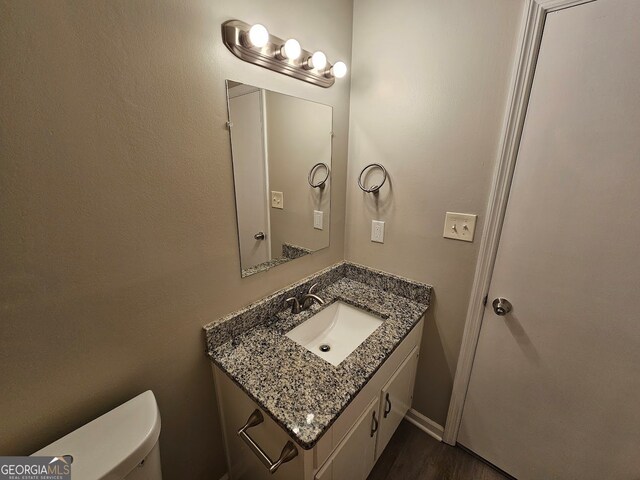 bathroom with wood-type flooring, vanity, and toilet