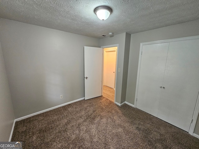 unfurnished bedroom with a textured ceiling, a closet, and carpet floors