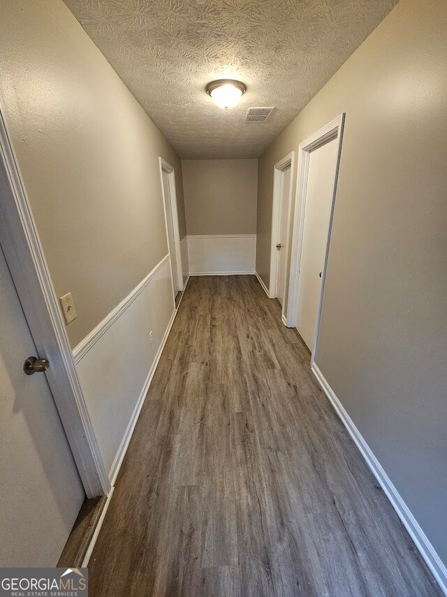 hallway featuring dark hardwood / wood-style flooring and a textured ceiling