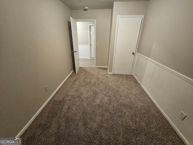 corridor featuring a textured ceiling and carpet floors