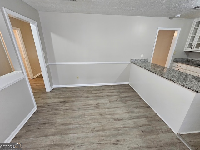 unfurnished dining area featuring a textured ceiling and light hardwood / wood-style floors