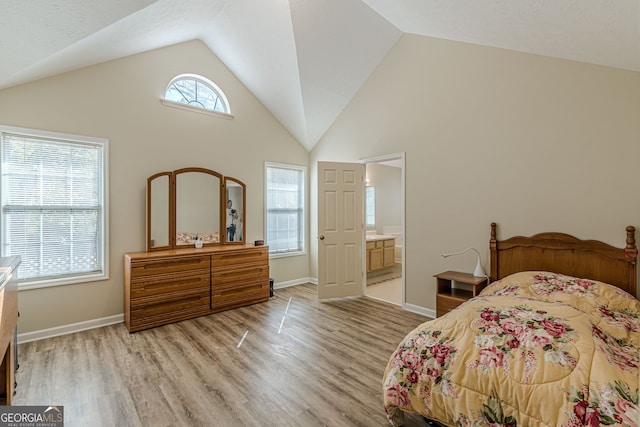 bedroom featuring high vaulted ceiling, ensuite bath, and light hardwood / wood-style floors