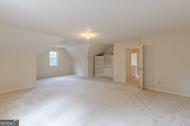 bonus room featuring a textured ceiling, light carpet, and vaulted ceiling