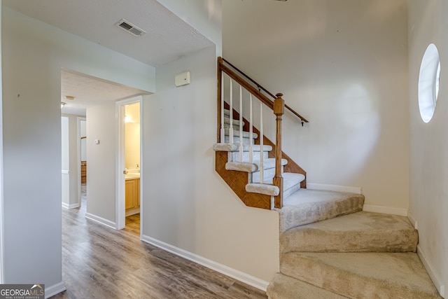 staircase featuring wood-type flooring and a textured ceiling