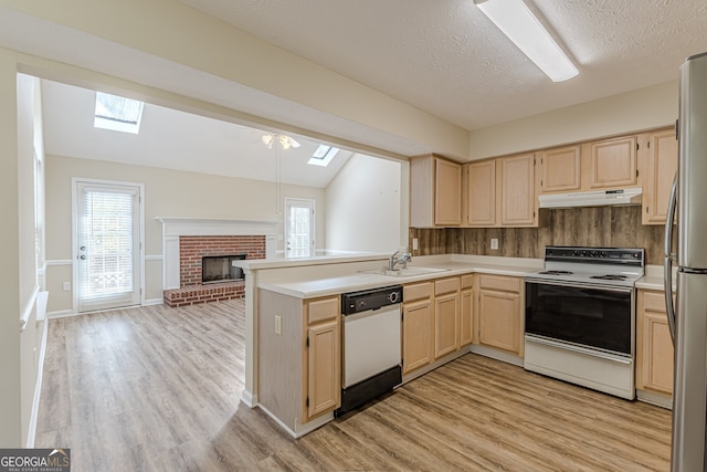 kitchen featuring vaulted ceiling with skylight, white appliances, light hardwood / wood-style floors, and a fireplace