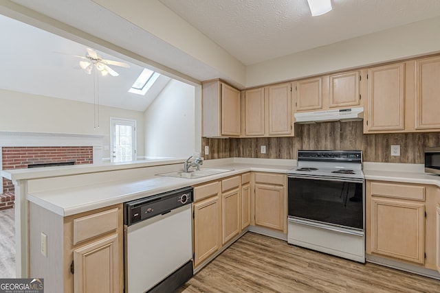 kitchen with vaulted ceiling with skylight, light wood-type flooring, white appliances, sink, and kitchen peninsula