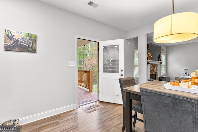 dining area featuring a stone fireplace and hardwood / wood-style floors