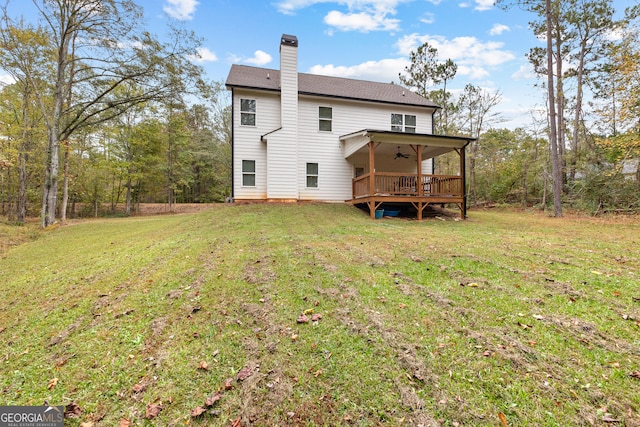 back of property with ceiling fan, a wooden deck, and a yard